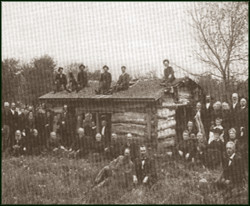 Historical picture of people around a log cabin